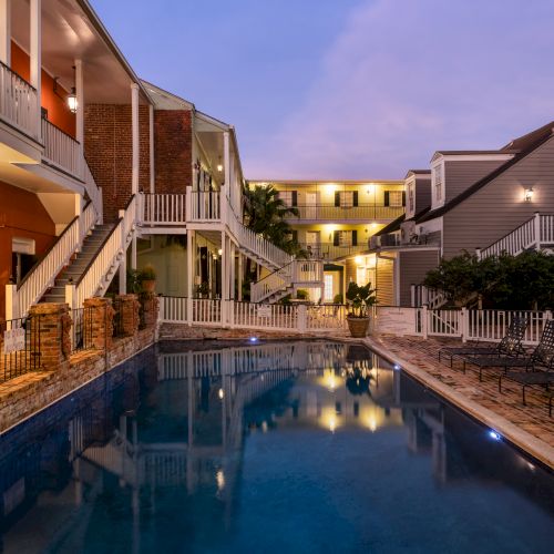 A serene outdoor swimming pool surrounded by multi-story buildings at dusk, with lit balconies and a peaceful ambiance.